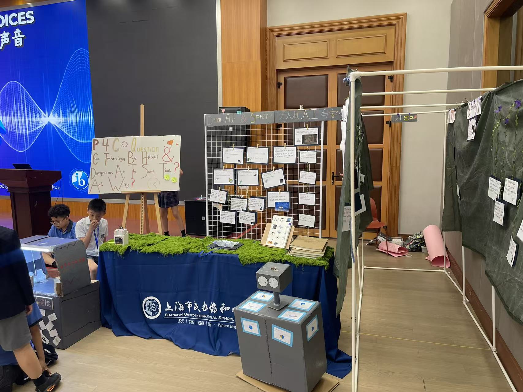 The drones group's walk-through gallery, with a P4C question on AI safety, a built robot, and drone safety tips hung for visitors to read.