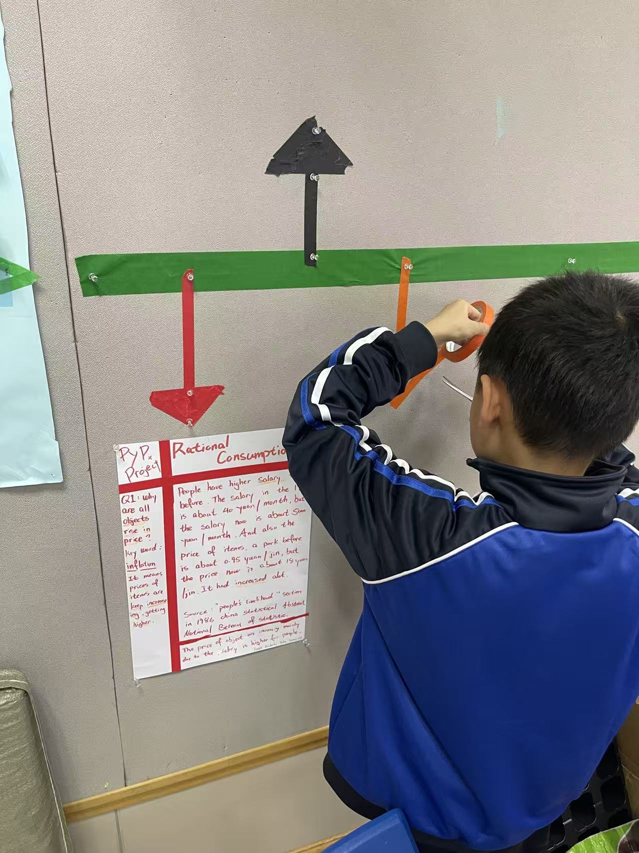 A student taping an arrow on the wall beside his group's first research poster